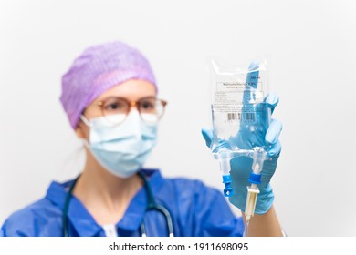 General Practitioner Holding Intravenous Drip Infusion. Doctor Handling IV Fluid Drip With Copy Space On White Background. Nurse Performing Intravenous Therapy.