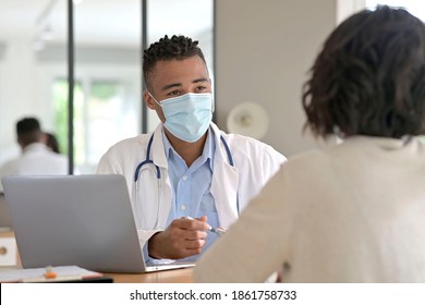 General Practitioner With Patient In Office, Wearing Surgical Face Mask During Pandemic