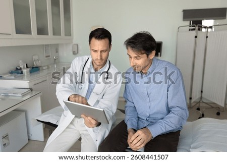 General practitioner showing lab test results to male patient, discuss medical diagnosis, electronic prescription, explain telemedicine platform using modern digital tablet device. Healthcare services