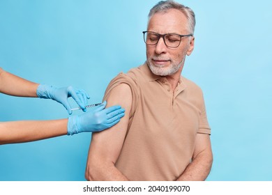 General Practitioner Vaccinates Old Male Model Gives Injection Against Coronavirus. Bearded Mature Man Cares About Health Gets Vaccine To Protecrt Himself From Flu Or Covid 19. Time To Vaccinate