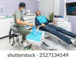 General shot of a dental office as a professional dentist dons his blue protective gloves to begin treating a mature adult patient.