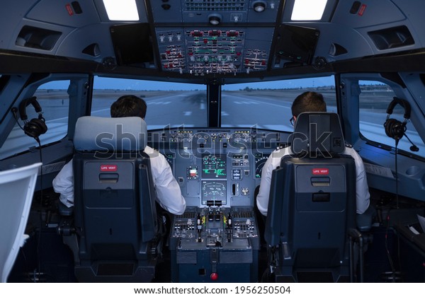 General view of the cockpit of a\
commercial flight simulator, with two pilots sitting in their seats\
preparing to start the flight during a flight\
practice