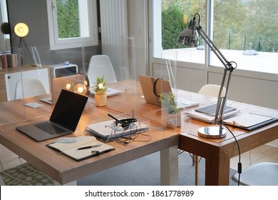 General view of open space office with desk and plexiglas separations