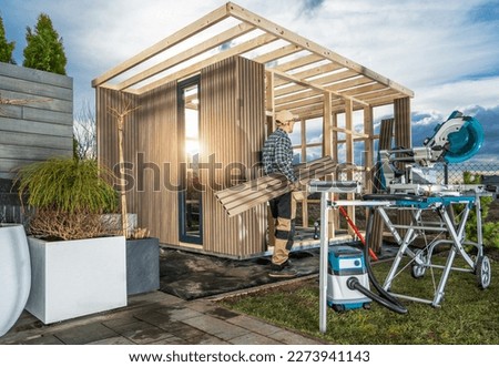 General Woodworker Building Elegant and Modern Garden Shed Which May Be Used as Backyard Sauna. 