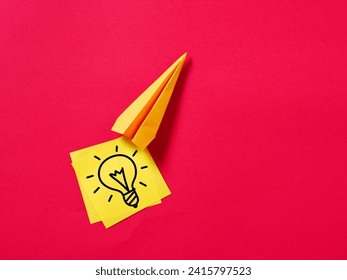 To generate and develop creative ideas. Boosting ideas and creativity. Paper plane carries a hand drawn light bulb symbol on yellow sticky note paper.