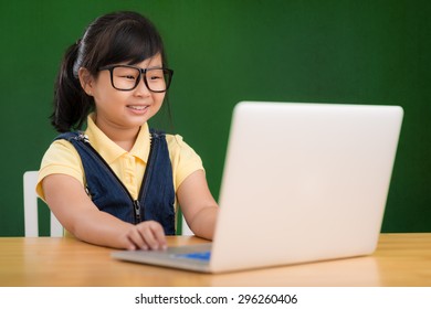 Generation Z: Little Asian Girl In Glasses Working On Laptop