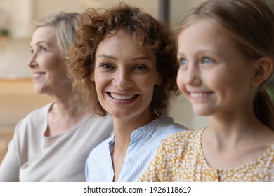 Generational Similarity. Three Generation Family Females Relatives Of Diverse Age Old Grandma Adult Mom Daughter Kid Sit In Row Together. Focus On Smiling Face Of Young Woman At Centre Look At Camera