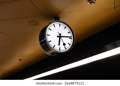 Generic analog clock inside underground train station platform in Europe. Close, looking up shot, no people
