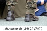 Generic anonymous army soldier legs boots closeup, camo uniforms, standing on the back of a military vehicle, detail shot. European American infantry soldiers simple abstract concept symbol, news shot