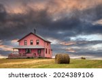 Generic architecture of the Magdalen Islands, where all the wooden houses are brightly painted. Sunset shot of a pink house on the hill. Image taken from a public position.