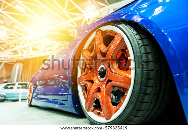 Generic blue\
sport car with orange wheel in\
sunlight