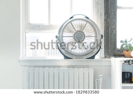 Generic and cheaply mass manufactured overseas in China unbranded white recycled plastic circular interior house or office fan three speed motor on a window sill shipped in a container