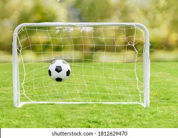 Generic Football (soccer) Ball Hits Net Of Mini Goal As Concept Of Recreational Sport And Family Fun