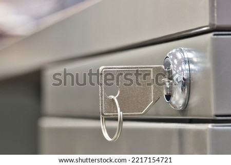Generic key inserted in a filing cabinet lock. Side view closeup with copy space and selective focus.