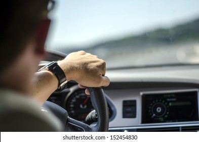 Generic photo of man driving a car through slight turn. - Shutterstock ID 152454830