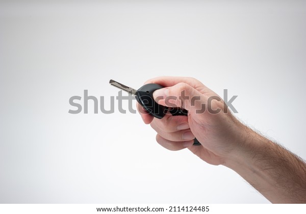 Generic plastic\
black car key fob held by Caucasian male hand. Close up studio\
shot, isolated on white\
background