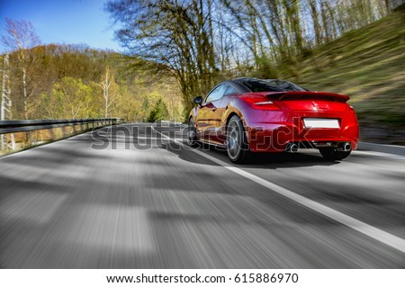 Generic red sports car driving fast on the open road