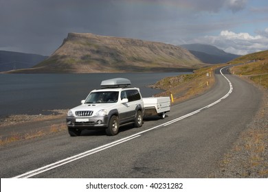 Generic SUV with a trailer in motion next to Hvalfjordur fiord in Iceland
