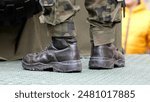 Generic unrecognizable infantry soldier on duty legs boots closeup, camo uniform, standing on a metal surface, detail shot. Army soldiers war operations simple abstract concept symbol, news shot