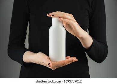 Generic White Bottle In Female Hands Against Low Light Backdrop. Product Photography, Blank Plastic Bottle With Space For Brand Text Or Logo