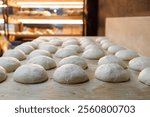 A generous amount of dough is currently resting on a rustic wooden table in a charming bakery, waiting to be transformed into bread