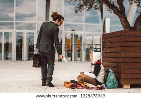 Generous businessman helping a homeless on the street