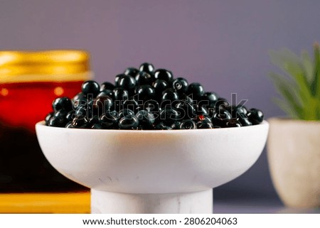 A generous serving of fresh bilberries is presented in a modern white bowl.