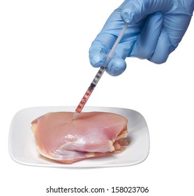 Genetic injection into raw chicken meat on square plate isolated on white background. Genetically modified food and syringe in hand with blue glove. Concept