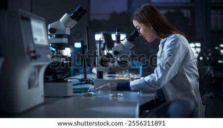 Genetic Research Scientist Using Microscope in an Applied Science Laboratory in the Evening. Portrait of a Beautiful Asian Lab Engineer in White Coat Developing New Medical Products