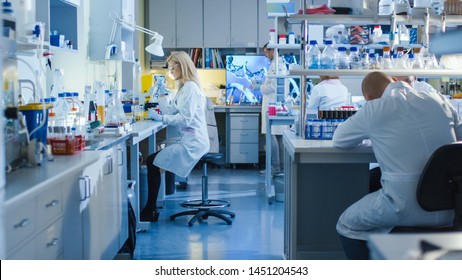 Genetic Research Scientists Work with Medical Equipment in a High Tech Research Laboratory. Female Scientist is using a Micro Pipette While Working with Colleagues.