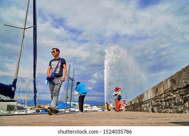 Geneva, Switzeland - September 21, 2018: Pier near famous Jet d'Eau fountain in Geneva lake and tourists on it in a nice day with blue sky and clouds in summer, Canton of Geneva, Switzerland