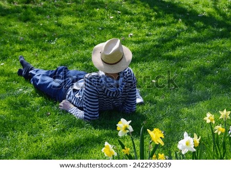 Geneva, Switzerland, Europe - single man laying in grass near  jonquils, leisure in Perle du Lac Park on the shore of Lake Geneva, April