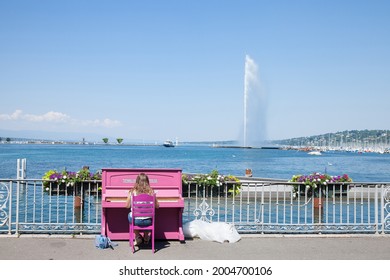 GENEVA, SWITZERLAND - JUNE 19, 2017: Female woman, amateur pianist, playing piano in front of Lake Geneva (Lac Leman) with its iconic Jet d'Eau (Water Jet), taken in a summer afternoon.