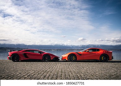 Geneva, Switzerland - March 2020: two red supercars, Lamborghini Aventador SV and Ferrari F12tdf attending a photoshoot at Lake Geneva in Switzerland.
