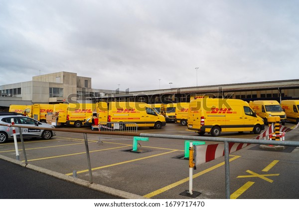 Geneva/Switzerland - September 2019/ DHL department\
in Geneva airport. Yellow cars of post delivery service at the\
parking lot.