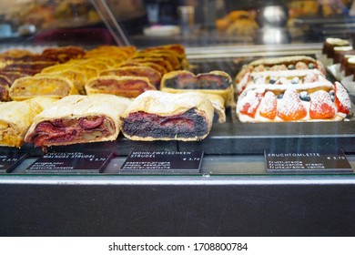 Geneva/Switzerland - September 2019: Variety of sweet strudels and 
belgian waffles with strawberries on display window in local sweets cafe.