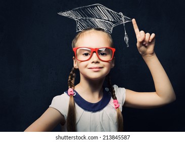 Genius Girl In Red Glasses Near Blackboard In Master Hat