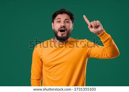 Genius man having idea eureka moment, pointing finger up on green background. Clever guy showing answer gesture or remembered what he forgot, memory concept. High quality
