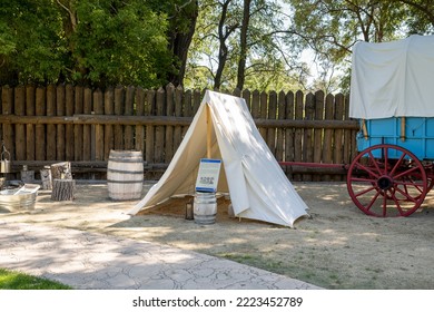 Genoa, NV, USA. 2022-09-17. Overnight Canvas Tent Beside A Blue Prairie Schooner Wagon With Red Wheels At The Mormon Station Historic Park. 