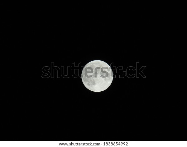 Genova, Italy - 09/25/2020: An amazing\
photography of the full moon over the city of Genova by night with\
a great clear sky in background and some\
stars