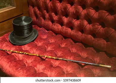 gentelman vintage style black hat and cane elegant classic man accesories on red furniture couch  