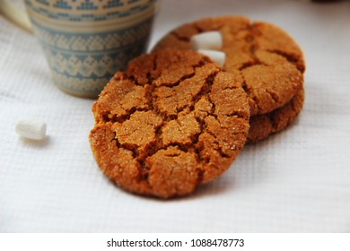 Gentle ginger honey biscuits with cracks and a cup with a drink. Picture of a mouth-watering round cookie