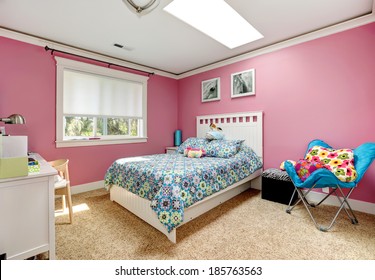 Gentle girls bedroom with white bed and pink walls. View of bed with blue bedding,blue chair