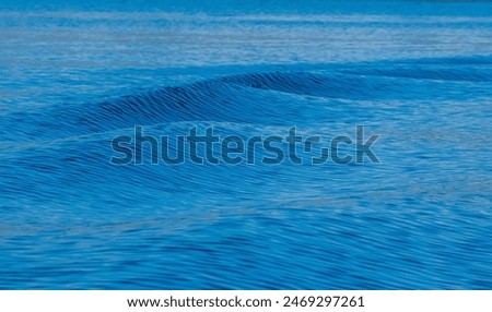 Ein Shortboard Sportler geht vom Strand auf das wellige Meer um zu Surfen. Blick von der Seite