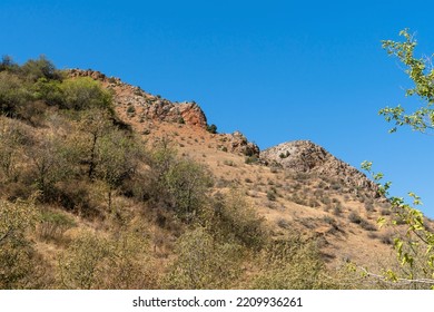 A Gentle Slope Of Pink Tuff With Sparse Vegetation In The Mountains Of The Caucasus..