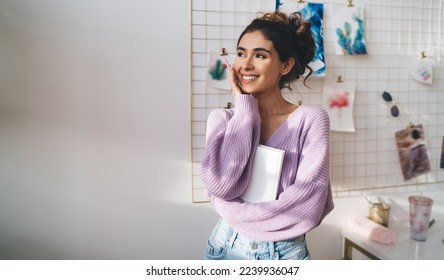 Gentle sweet girl in purple sweater posing at camera smiling sincerely from. Radiant brunette woman with beautiful appearance holds diary in hands. Positive female student with notebook organizer  - Shutterstock ID 2239936047