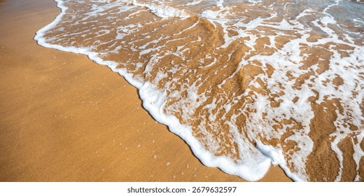 Gentle waves rolling and breaking over bright golden sandy beach