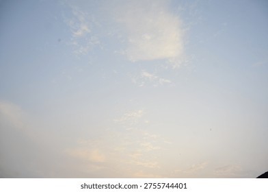 Gentle, wispy clouds float in a serene, pale blue sky, illuminated by the soft light of dusk.