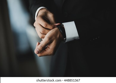 Gentleman in black suit puts on a black watch