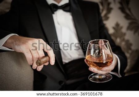 Gentleman holding glass of cognac and cigar